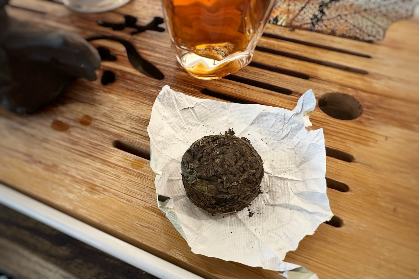 Tea cake on a piece of paper with a glass of tea in the background on a wooden surface.