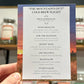 Menu card for 'The Mountains Out' Cold Brew Flight held by a hand with blurred jars in the background