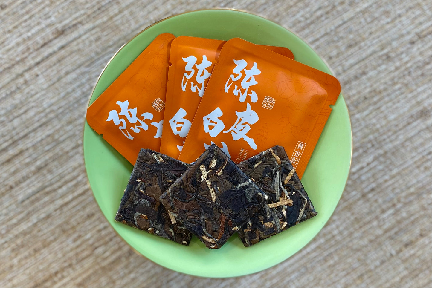 Three fanned orange envelopes beside three fanned white tea cakes with pressed-in orange peel slices