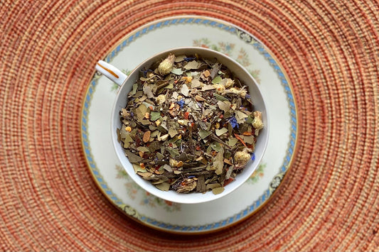 teacup full of yaupon holly, flowers, and spice