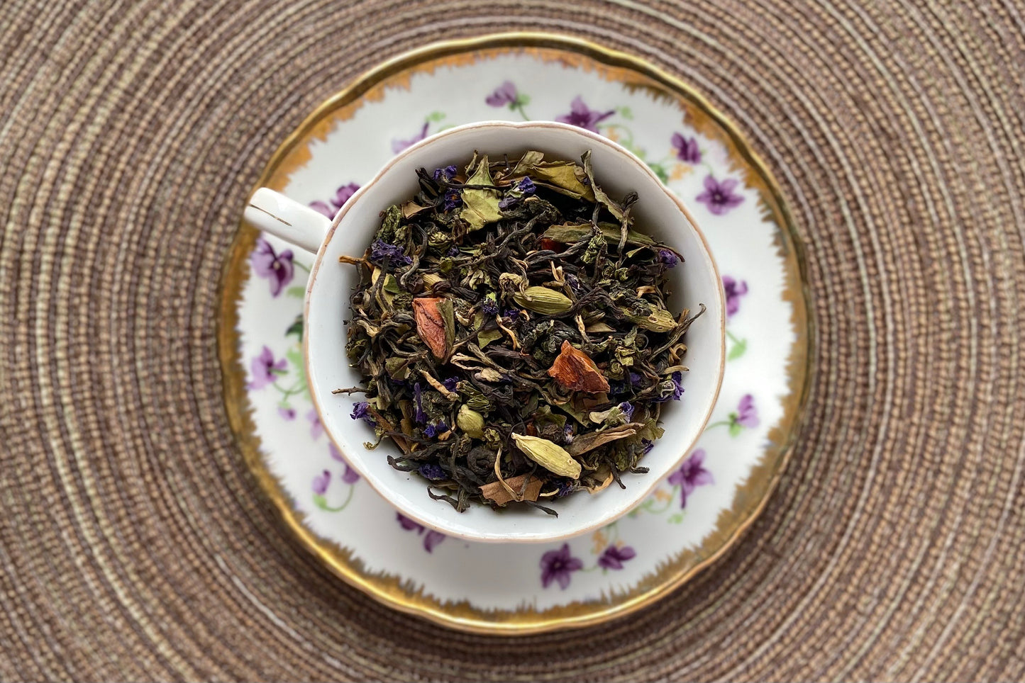 Violet decor teacup full of tea, flowers and spices