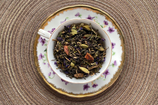 Violet decor teacup full of tea, flowers and spices