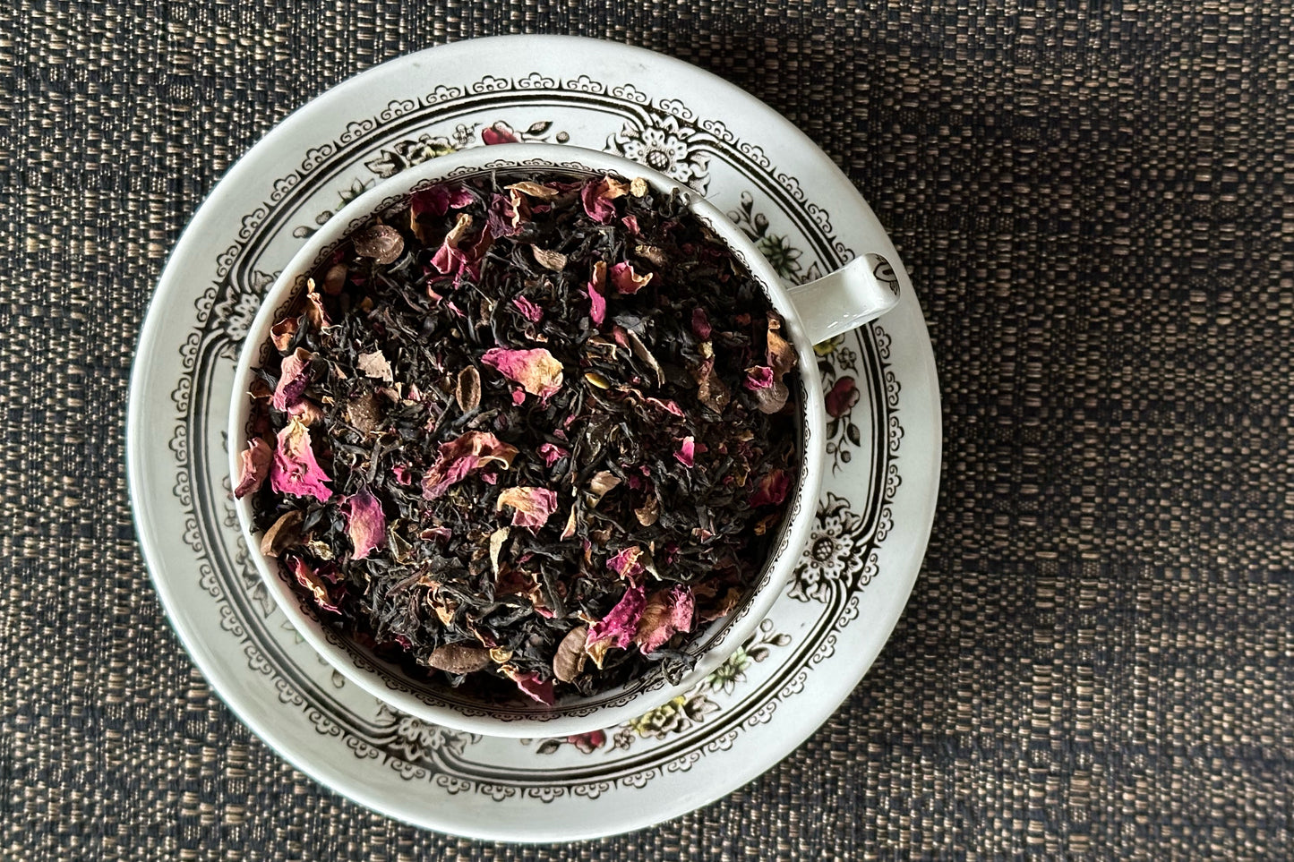 teacup full of black tea, green chili flake and rose petal