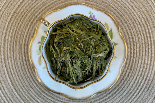 Teacup full of flat green tea leaves