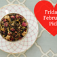 Tea leaves in a teacup on a white plate with a red heart-shaped label reading 'Friday's February Pick!'.