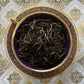 blue and gold teacup full of gold tipped dark yellow tea leaves