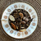 Teacup full of aged tea, fig, almond and coffee beans