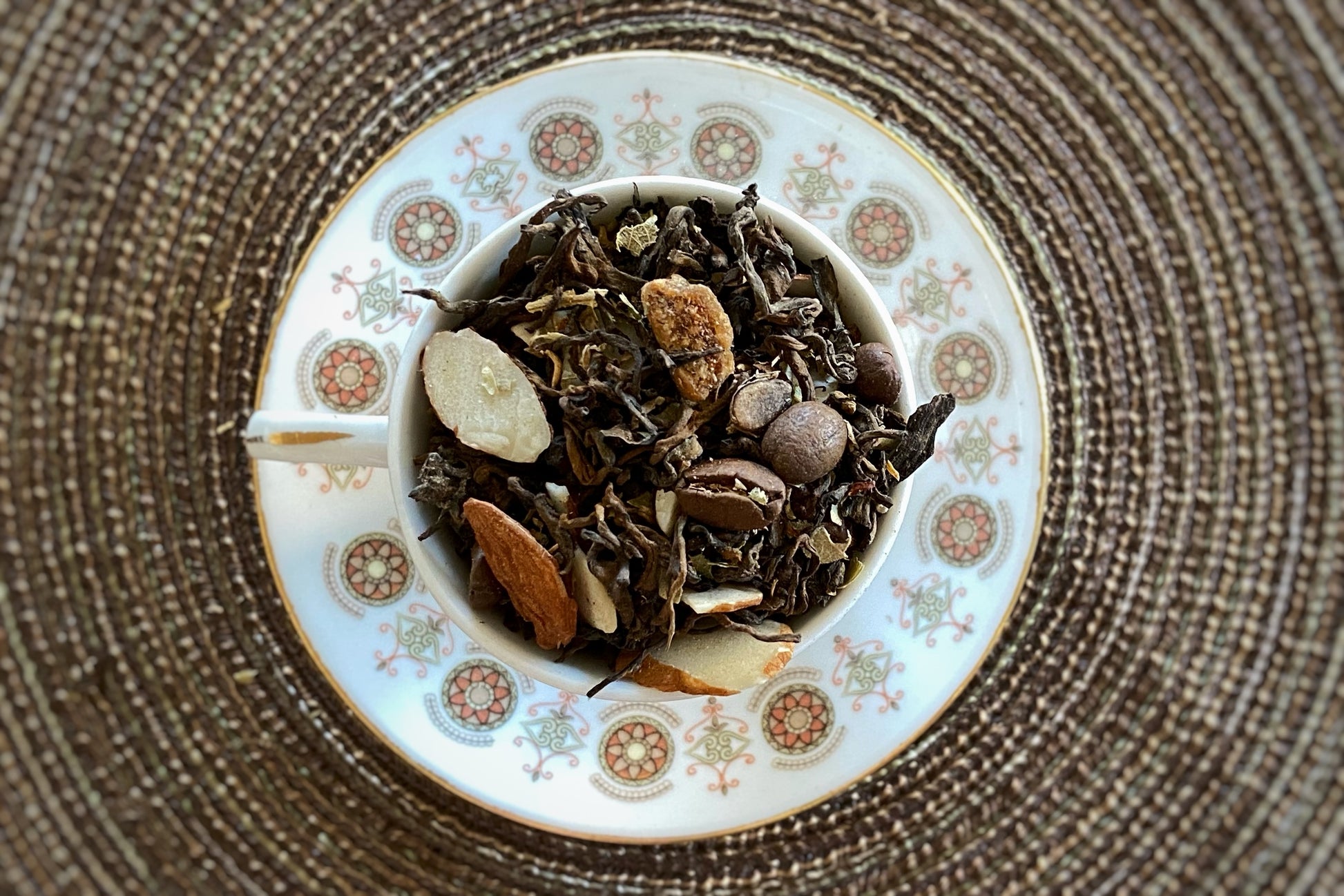 Teacup full of aged tea, fig, almond and coffee beans