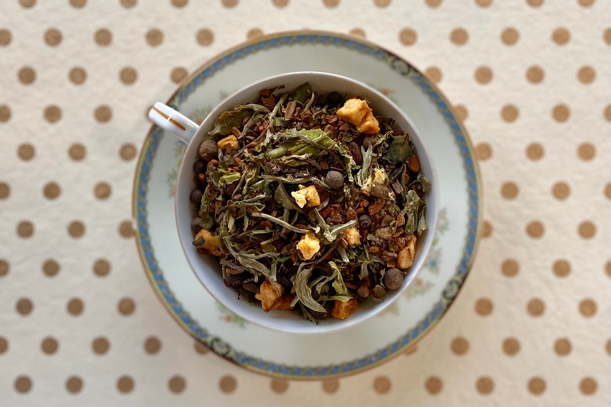 Blue and white teacup full of white tea, fruit, spices, and glitter