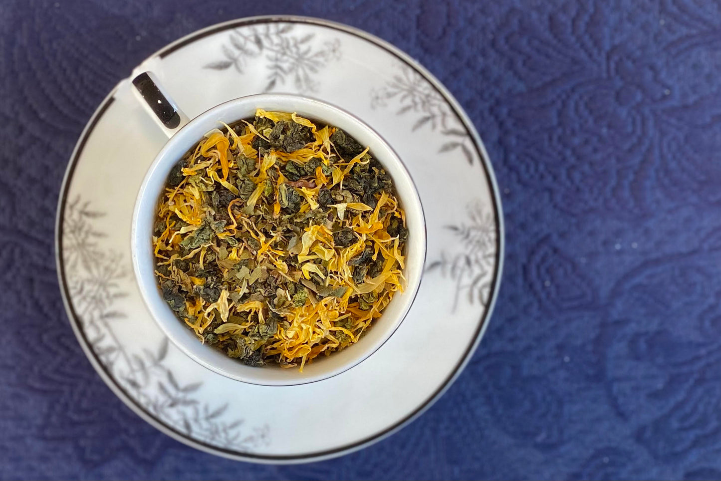 teacup full of rolled oolong and marigold petals