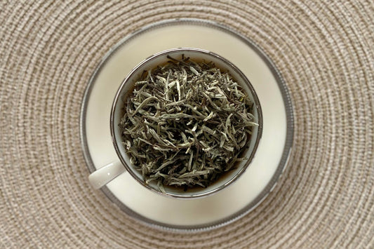 White teacup full of fuzzy silver needle white tea