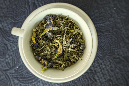 teacup full of white tea with berries and blue flowers