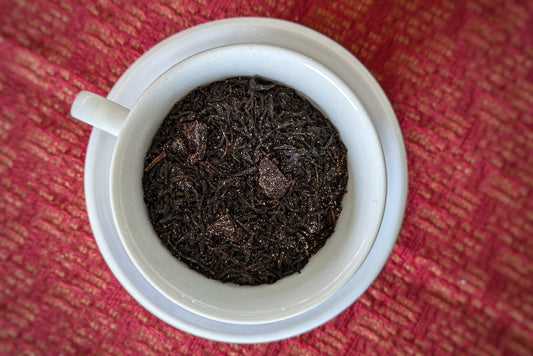 teacup full of black tea with cherry and gold glitter