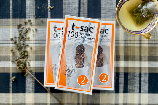 Three boxes of t sac filters beside a scoop of tea and teacup of brewed oolong tea