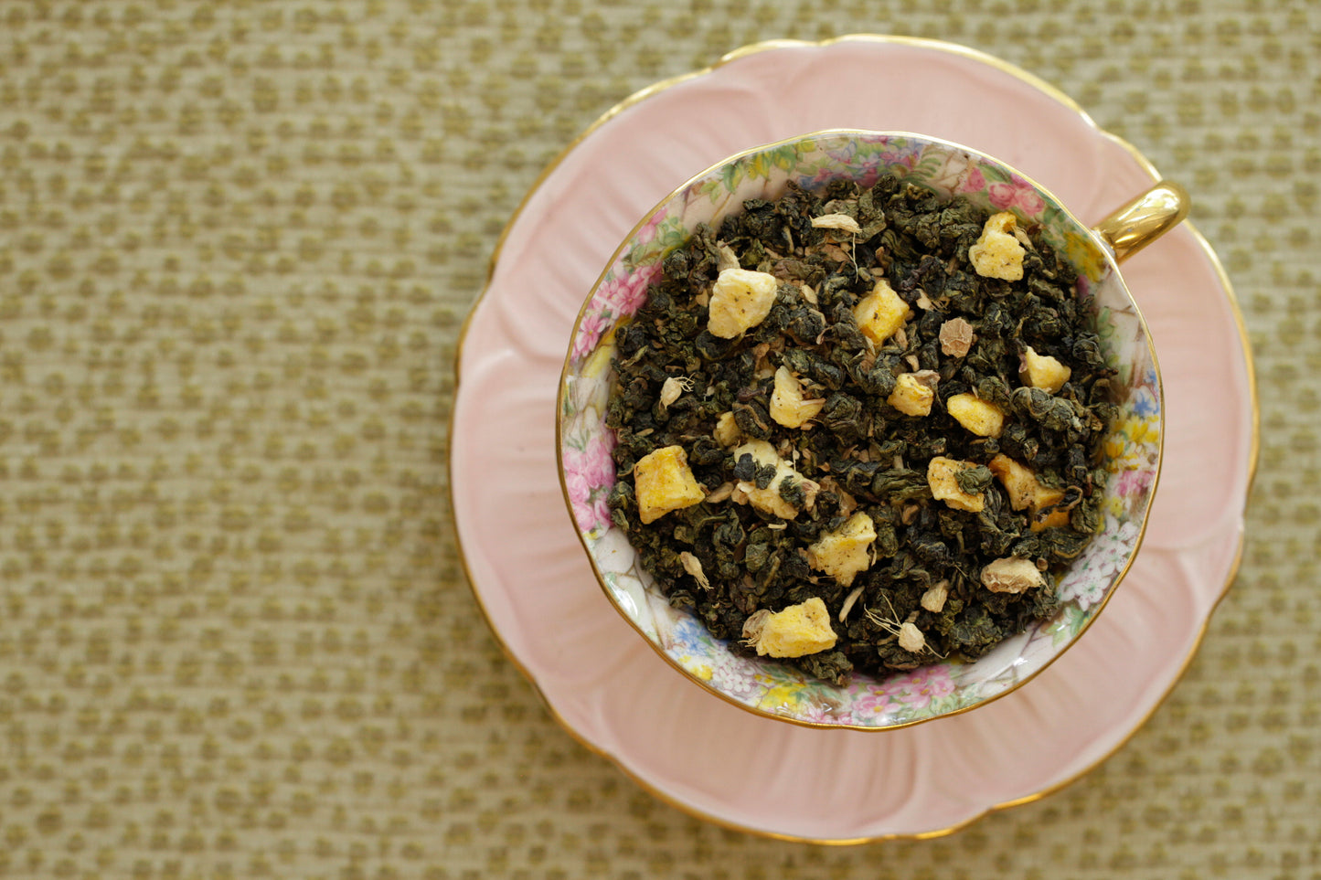 teacup full of rolled green leaves and peach pieces